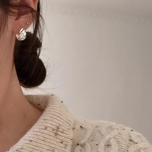 Detailed view of silver ripple textured stud earrings on model for a minimalist look