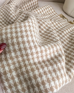 Detailed view of beige houndstooth wool fabric texture and gold metal clasp on a handbag