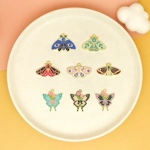 Macro shot of 8 colorful enamel butterfly and moth charms with crescent moon motifs