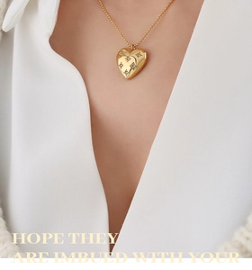 Detail of a gold heart pendant necklace with star-set diamonds on a white suit model