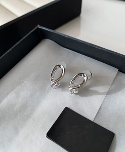 Macro shot of silver drop earrings with clear zircon stones in a premium jewelry box