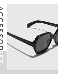 Detailed close-up of hexagonal sunglasses with black glossy frame and tortoiseshell temple
