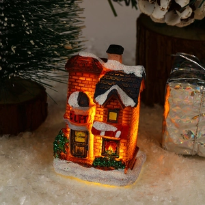 Close-up of LED glowing Christmas house ornament with warm orange lights and faux snow detail