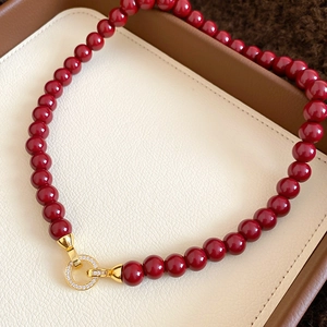 Macro shot of red agate beads and a gold circle clasp with micro-inlaid zircons