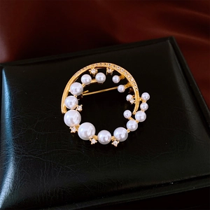Detailed shot of a 24k gold plated pearl brooch with sparkling crystals on leather box