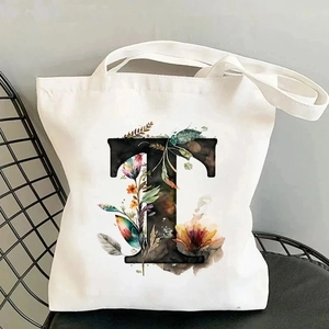 Close-up of canvas tote bag with floral letter T print on a black metal chair