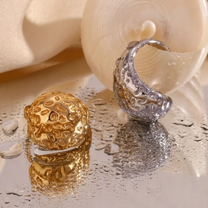Detailed view of 18K gold and silver plated hammered rings on a reflective water surface