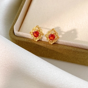 Detail of vintage rhombus stud earrings with red zircon in gold hollow design