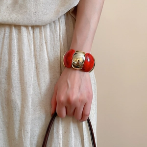Macro view of oversized acrylic marbled bracelet with a gold spherical link on wrist