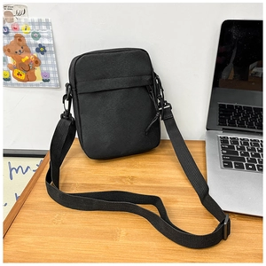 Detail of minimalist black crossbody bag on a desk with durable canvas fabric texture
