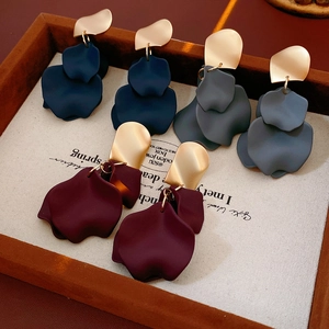 Close-up of irregular flower petal earrings in navy blue, burgundy, and grey on a tray