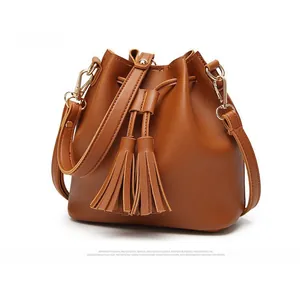 Detailed side view of brown PU leather bucket bag with tassels and drawstring closure