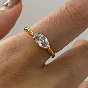 Detailed close-up of a marquise-cut crystal gold ring worn on a finger