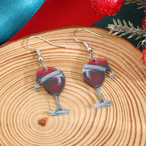 Macro detail of acrylic Christmas wine glass earrings on a festive wooden surface