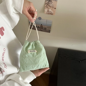 Detail of light green drawstring pouch with seersucker texture and white brand label