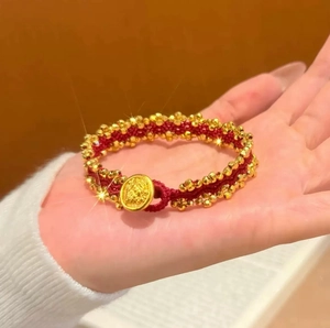 Rotes geflochtenes Armband mit vergoldeten Perlen und einem runden Relief-Charm