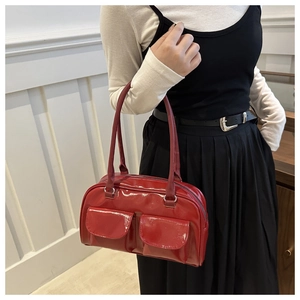 Close-up of red patent leather Boston bag with double front flap pockets and glossy finish