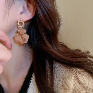 Detail of gold metal hoop earring with matte light brown petal pendants on female model