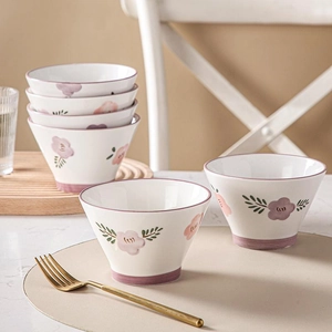 Floral ceramic conical bowl set with pink flowers and purple trim in a soft lighting scene