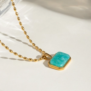 Detailed shot of 18k gold beaded chain necklace with rectangular blue stone pendant