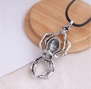 Detailed macro view of silver metal spider pendant with intricate skeletal texture on black cord