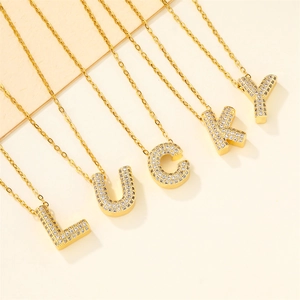 Five gold-plated necklaces with zircon pendants spelling LUCKY on a beige background