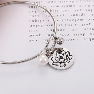 Detailansicht eines silbernen Edelstahl-Armreifs mit weißer Perle und Lotus-Anhänger