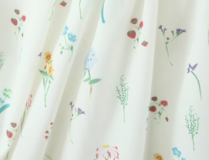Detail von Blumen- und Erdbeerdruck auf weißem Stoff mit sichtbarer Textiltextur