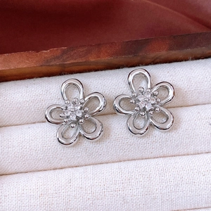 Detailed macro view of silver hollow flower stud earrings with sparkling zircon center