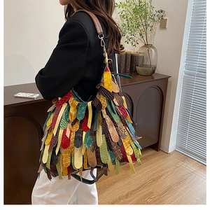 Detail of colorful patchwork leather hobo bag with fringe and wide shoulder strap
