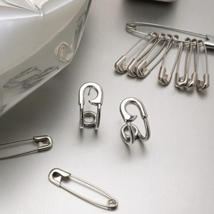 Macro detail of silver safety pin earrings with a polished metallic finish