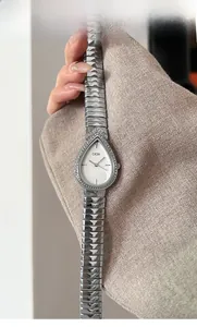 Detail of silver water-drop quartz watch with crystal bezel worn on a female wrist