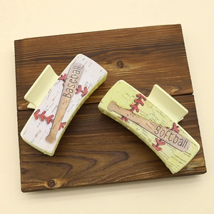 Detailed top view of PU hair claws featuring baseball and softball patterns on wood