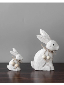 Detail van twee witte paashaasfiguren met houttextuur en decoratieve jute touwtjes