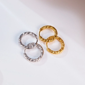 Detailed close-up of gold and silver hoop earrings with diamond-cut geometric texture