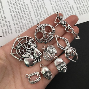 Detailed close-up of eight silver alloy Halloween charms including skull and pumpkin
