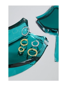 Detail of silver and gold S925 sterling silver hoop earrings on broken glass surface