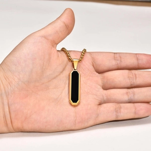 Macro detail of gold-plated rectangular pendant with black inlay and ball chain