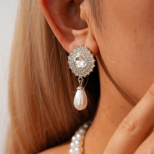 Close-up of vintage rhinestone drop earrings with a pear-shaped pearl on female model