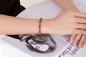 Detailed close-up of a pink beaded bracelet featuring a heart toggle clasp on a wrist
