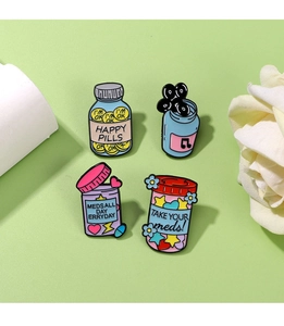 Detail of four colorful enamel pins with medical theme and happy pills slogans