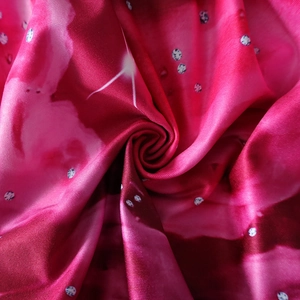 Close-up of red glossy polyester fabric with white polka dot print texture details