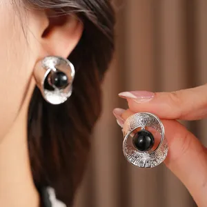 Minimalist silver twisted hollow earrings with black bead detail worn on ear