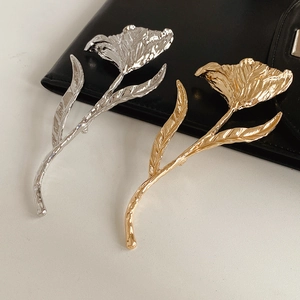 Detailed view of silver and gold tulip flower brooches with natural metallic texture