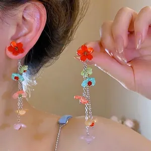 Detail of floral tassel earrings with colorful resin petals and long silver chain