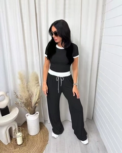 Detail view of black ribbed knit two-piece set with white trim on female model