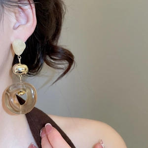 Close-up of model wearing acrylic irregular gold earrings with transparent brown resin detail