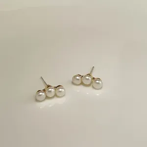 Detailed macro view of triple white pearls in a linear gold stud earring setting