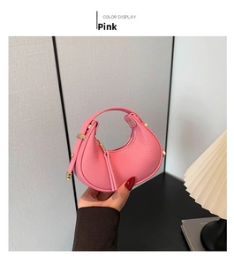 Close-up of pink crescent moon bag with lychee texture leather and gold hardware detail
