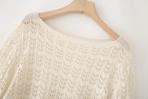 Detailed close-up of off-white pointelle knit sweater with scalloped openwork design